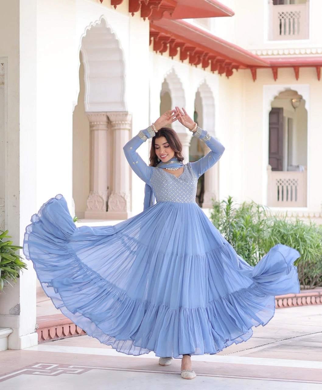 Woman in a blue dress dancing in front of an architectural building